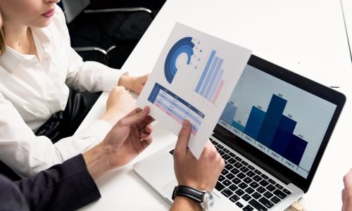 Business professionals discussing data charts and graphs in a modern office setting.