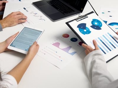 Team analyzing financial charts and digital reports during a business meeting.